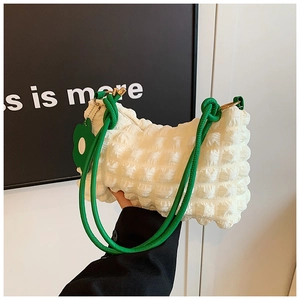 Detail of cream bubble texture shoulder bag with green knotted strap and floral charm