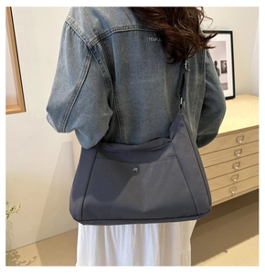 Detailed back view of a dark grey canvas crossbody bag with adjustable strap and metal button
