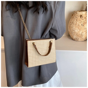 Detail of woven houndstooth pattern and brown leather trim on the shoulder tote bag