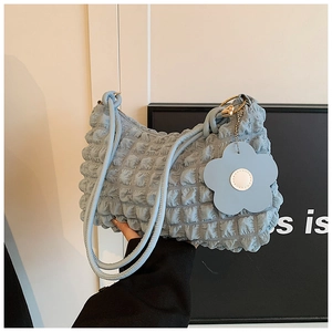 Detail of light blue bubble textured tote bag with flower pendant and shoulder strap