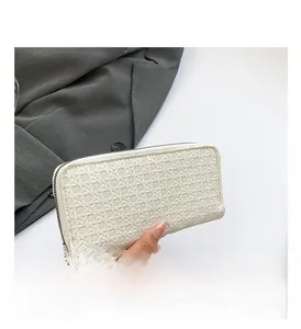 Macro shot of white woven texture and zipper detail on a long designer clutch wallet