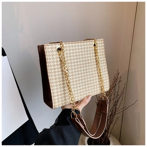 Detail of houndstooth tote bag with gold chain strap and brown leather handle