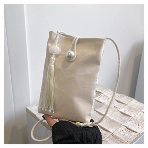 Detail of cream crossbody phone bag with pearl closure, wrinkled fabric, and long tassel