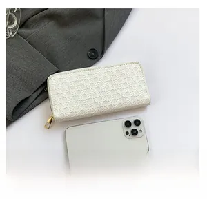 Detailed comparison of white woven long clutch wallet next to a smartphone for size
