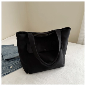 Détail du grand sac cabas noir en toile avec poche frontale et bouton métallique argenté
