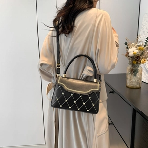 Black leather crossbody bag with wave chain and heart metal detail on beige coat