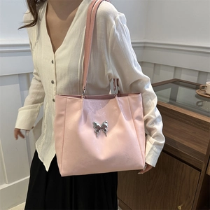 Sac cabas rose en cuir synthétique avec boucle papillon argentée porté par un mannequin