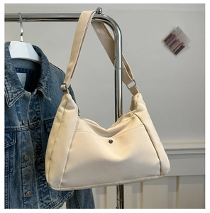 Detail view of large cream canvas tote bag with front pocket and metal snap button closure