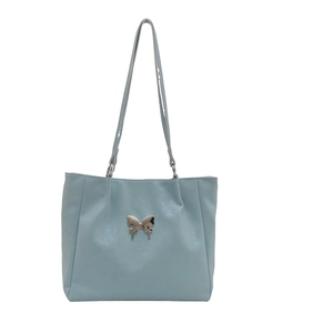 Grand sac cabas bleu clair avec ornement papillon en métal sur fond blanc épuré