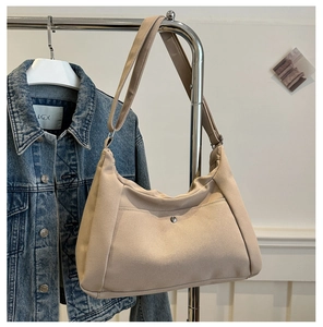 Detail of beige canvas crescent bag with adjustable strap and metal buckle pocket