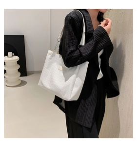 Detail of white woven texture tote bag with minimalist FASHION label on model