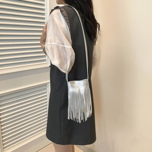 Silver fringe crossbody bag with metallic tassels and slim strap worn by a model