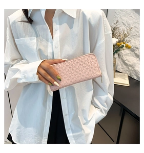 Macro detail of soft pink woven leather wallet featuring a premium golden zipper closure