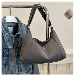 Detail of dark grey hobo bag with V-shaped pocket and metallic snap on hanger