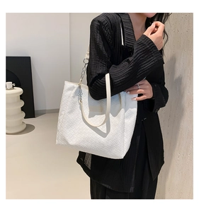 Detail of white woven tote bag featuring soft leather texture and silver chain strap