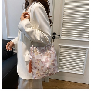 Détail des broderies papillon roses et des glands en soie sur le sac seau élégant