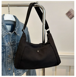 Detail view of black canvas hobo bag with wide adjustable strap and metal buckle