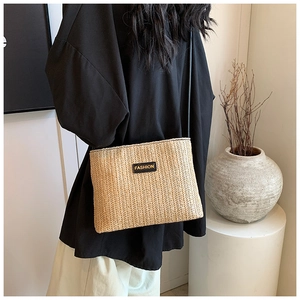 Dettaglio della trama a V di una borsa a secchiello in paglia beige con patch nera