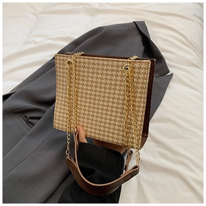 Detail of houndstock pattern handbag with brown leather handle and gold chain straps