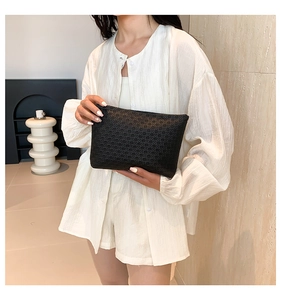 Detail of black clutch bag showing luxury geometric woven texture and minimalist design