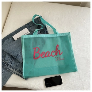 Detail of mint green mesh beach tote featuring pink Beach Vibes lettering and soft texture