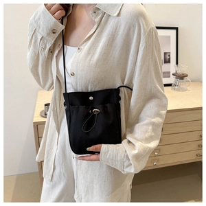 Détail du sac à bandoulière noir en nylon avec cordon de serrage et boucle sur un modèle