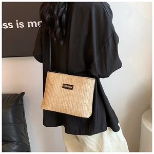 Dettaglio della borsa a tracolla in paglia beige intrecciata con toppa fashion nera
