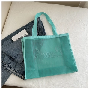 Detail of mint green mesh beach tote bag with white hand-lettered Beach print