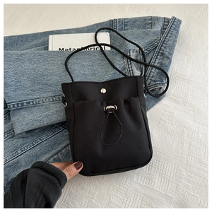 Détail d'un sac téléphone en nylon noir avec cordon de serrage et bouton pression chic