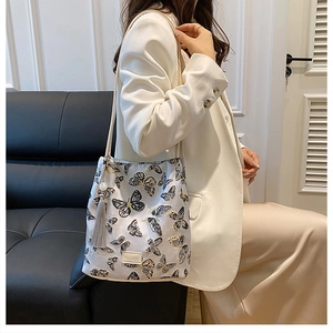 Détail de la broderie papillon et du pompon gris sur un sac seau élégant pour femme