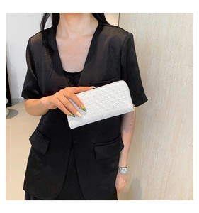 Close-up of white woven texture clutch with gold zipper held by a model