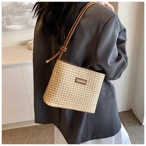 Modella indossa una borsa a tracolla in paglia bicolore con patch in pelle e spalline fini
