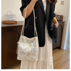 Détail du sac à épaule brodé de papillons avec pompon et plaque dorée Fashion