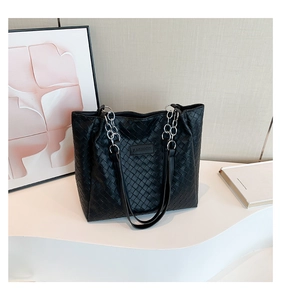 Detailed close-up of premium black woven texture and metal chain strap on a tote bag