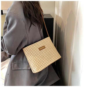 Dettaglio borsa in paglia pied-de-poule con etichetta FASHION in pelle marrone