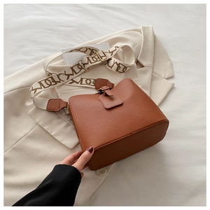 Close-up of brown lychee grain leather bucket bag with geometric print wide strap