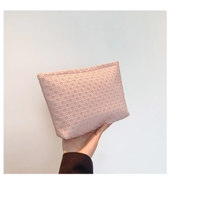 Close-up of pink envelope clutch bag featuring star-shaped woven texture and zip closure
