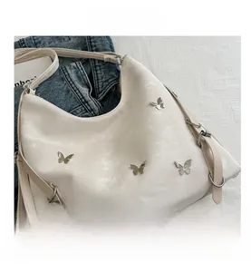Détail du sac hobo blanc avec ornements papillons argentés et bandoulière large