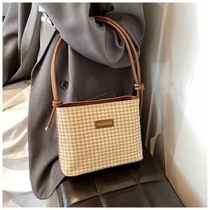 Dettaglio borsa a secchiello intrecciata con tracolla in pelle marrone e logo moda