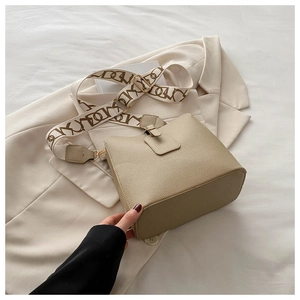 Detail of cream bucket bag with lychee texture and geometric patterned canvas strap
