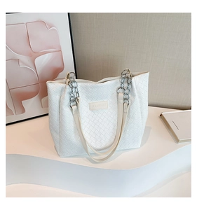 Detail showing white woven tote bag with silver chain and FASHION label on white pedestal