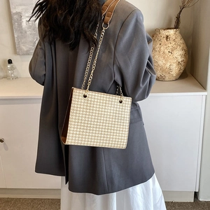 Stylish houndstooth tote bag with gold chain strap shown on model in grey blazer