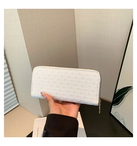 Detail view of a white woven texture long wallet with gold zipper held in a modern setting