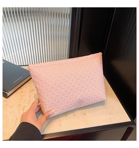 Detailed view of pink woven texture on large capacity envelope clutch held by hand