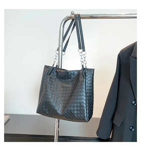 Detail of black woven leather tote bag featuring a silver chain strap and fashion plaque