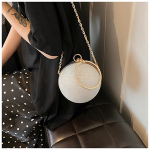 Detail of silver glitter spherical evening bag with gold ring handle and chain strap
