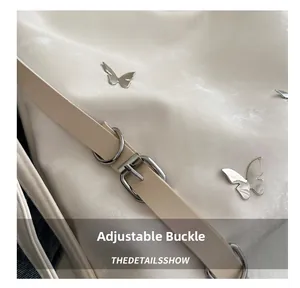 Détail de la bandoulière réglable avec boucle argentée et papillons sur un sac fourre-tout