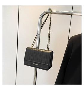Detail of black vertical quilted handbag with gold chain strap and fashion logo