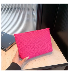 Detail of rose pink envelope clutch featuring a geometric woven texture and zipper closure