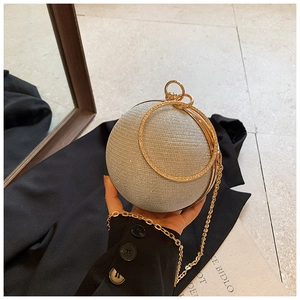 Detailed shot of a silver glitter sphere evening bag with golden ring handles and chain